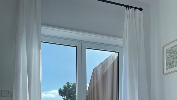 A bedroom with a large bed, a view of the outdoors, and a wooden wall.