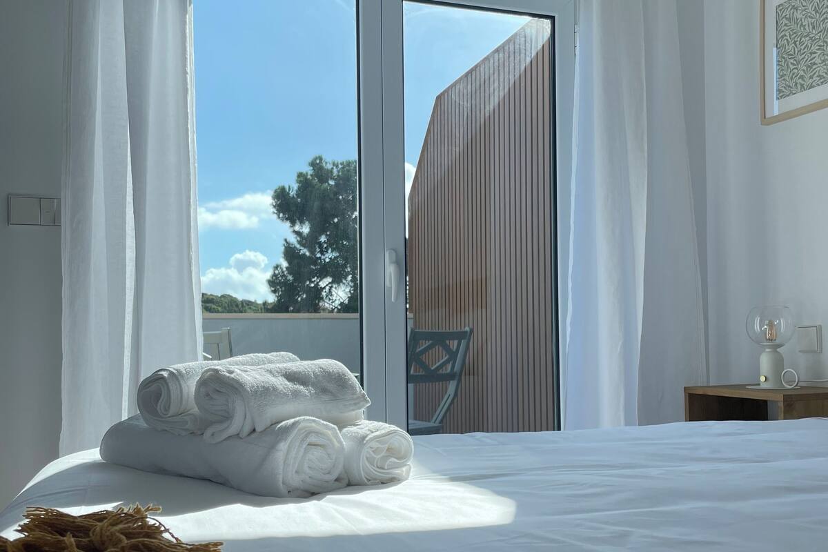 Ein Schlafzimmer mit einem großen Bett, Blick ins Freie und einer Holzwand.