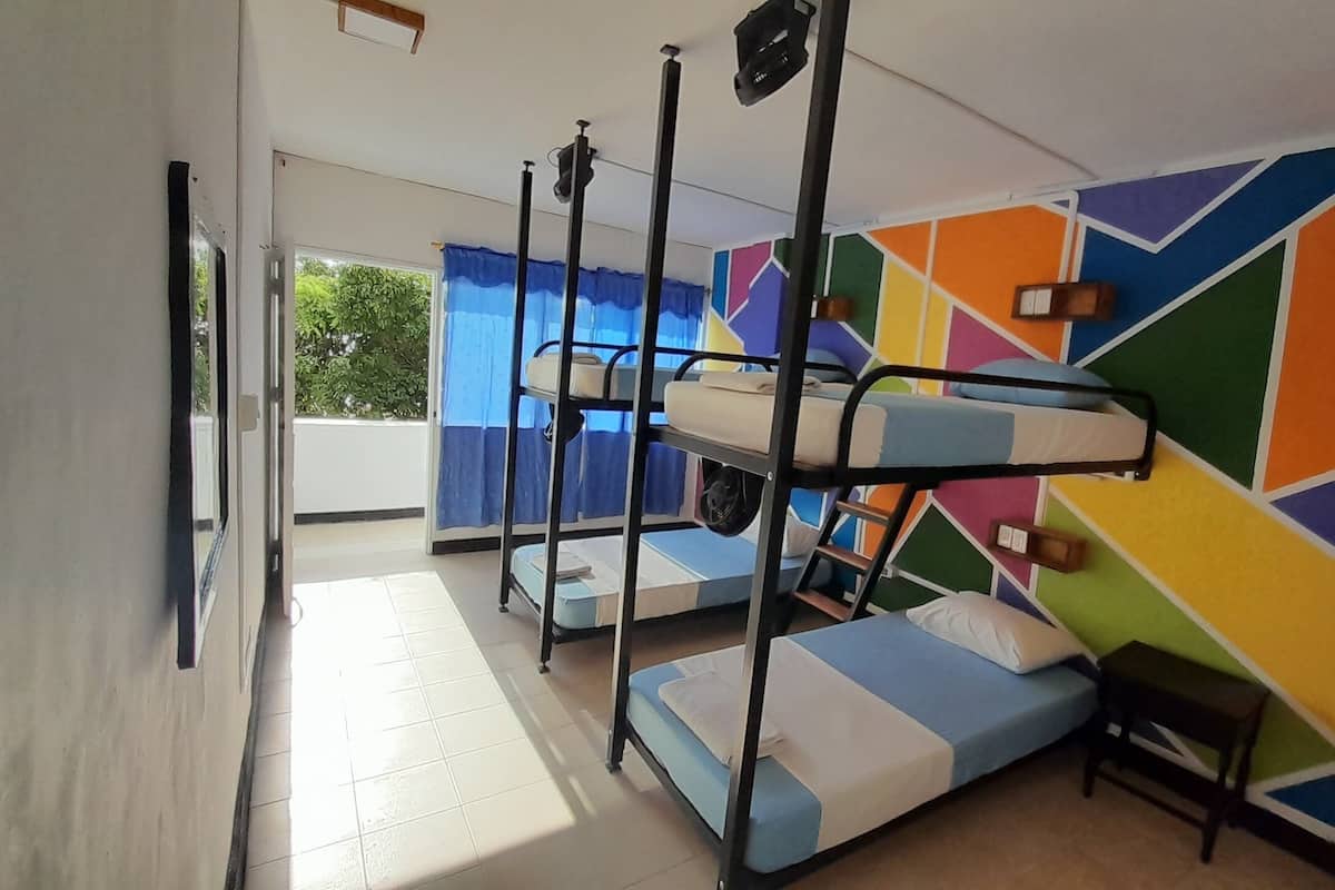 A dormitory room with bunk beds, a small table, and a colorful geometric wall design.