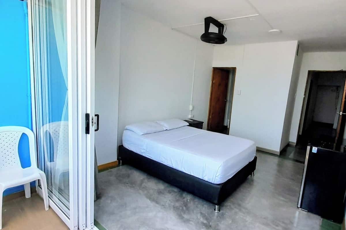 A bedroom with a bed, a chair, a desk, and a wardrobe.