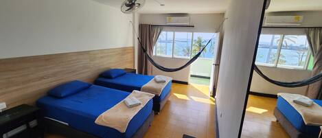 Habitación de hotel con dos camas, una hamaca y vista al mar.