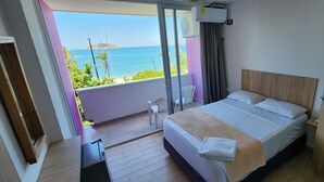 A bedroom with a bed, a nightstand, a chair, and a view of the ocean. - panamerican hostel  (Santa Marta)