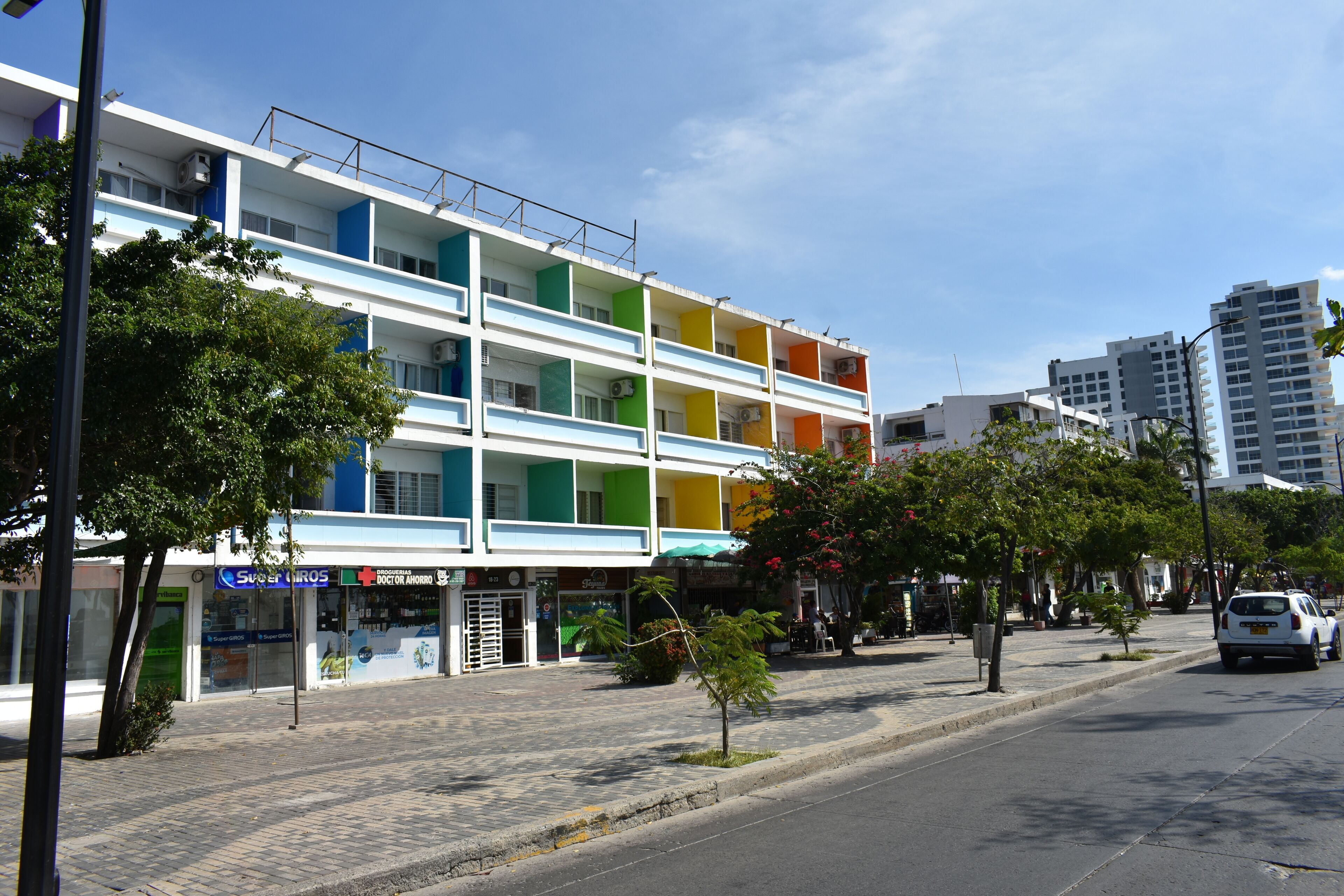 A multi-story building with a colorful facade, a sidewalk, and a street.