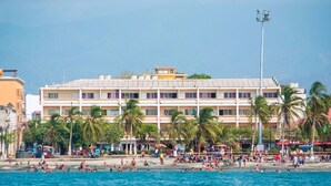 A beachfront hotel with multiple balconies, palm trees, and a sandy beach. - panamerican hostel  (Santa Marta)