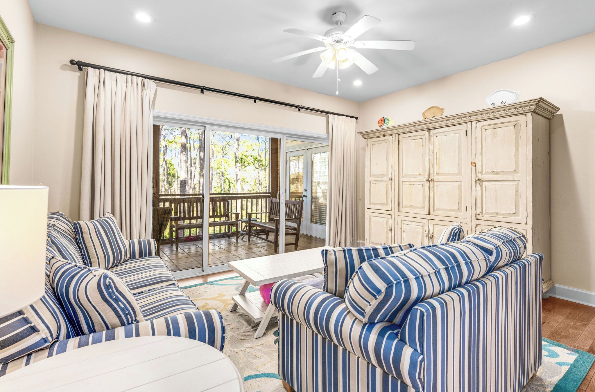 A room with striped sofas, a white table, and a cabinet.