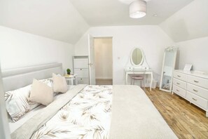 Ein Schlafzimmer mit einem Bett, einem Schreibtisch, einem Spiegel und einer Kommode.