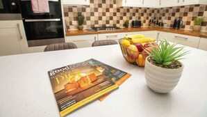 A kitchen with a checkered backsplash, a stove, an oven, and a magazine on the counter. - Warm & Inviting Home | Free Parking & Wi-Fi (Lincoln)