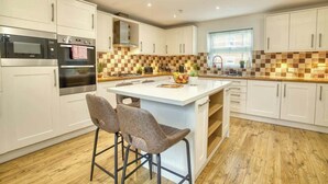 A modern kitchen with white cabinets, a central island, and a checkered backsplash. - Warm & Inviting Home | Free Parking & Wi-Fi (Lincoln)