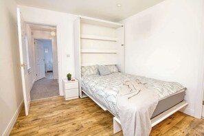 Ein Schlafzimmer mit einem Bett, einem Nachttisch und einer kleinen Pflanze.