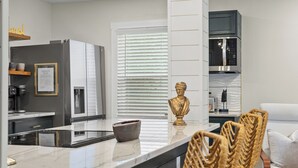 Une cuisine moderne dotée d’un îlot central, de tabourets de bar, d’un luminaire décoratif et d’une statue.