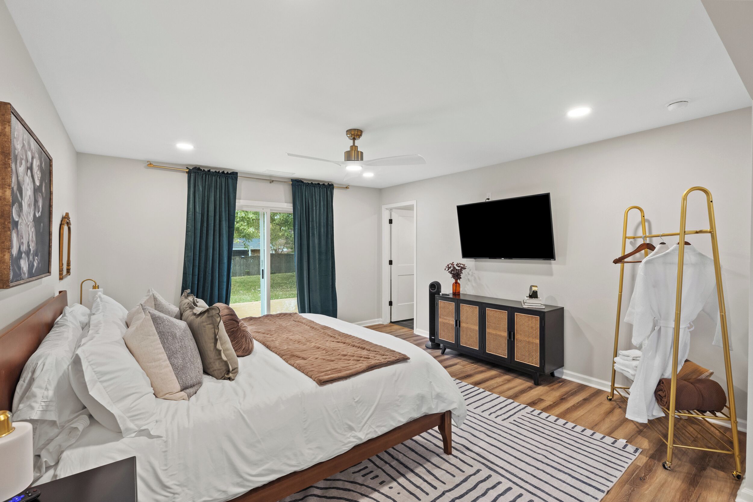 A modern bedroom with a bed, a TV, a wardrobe, and a balcony.