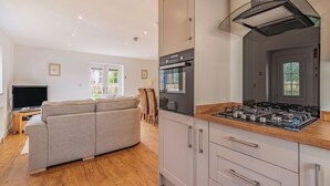 A modern kitchen with a built-in stove, wooden countertop, and white cabinets. - 1 bedroom accommodation in Bempton (Bempton)