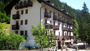 A multi-story hotel with balconies, a sign indicating 'HT Tea San Pellegrino', and a mountainous backdrop. - Ht TEA San Pellegrino (Canale d'Agordo)