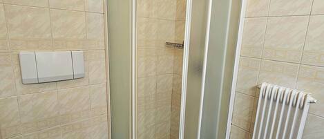 Une salle de bain avec une douche à parois de verre, des toilettes et un porte-serviettes.