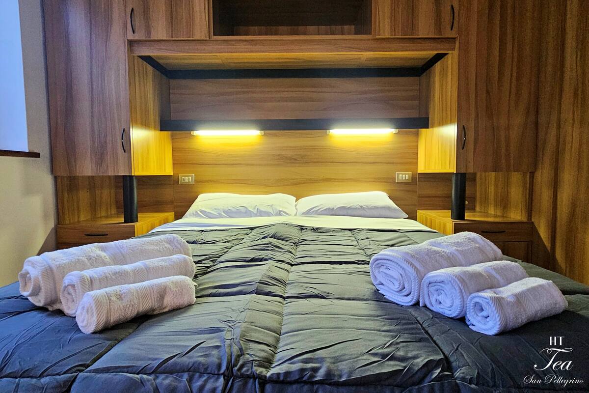 A hotel room with a bed, two nightstands, and a wooden headboard with built-in lighting.