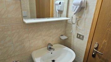 Un bagno con due lavandini, uno specchio e un asciugacapelli fissato alla parete.