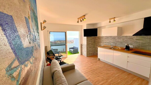 Eine moderne Küche mit einem großen Fenster, ein Essbereich mit einer Couch und Blick auf die Stadtlandschaft.