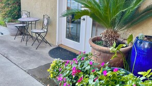 Eine Terrasse mit Tisch und Stühlen, einem Blumentopf und einer Tür mit Fenster.