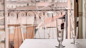 Dos vasos transparentes sobre una mesa, con vista a un balcón y edificios al fondo.