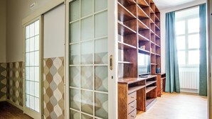 Una habitación con puerta corrediza, un escritorio de madera con cajones y un ventanal con cortinas.