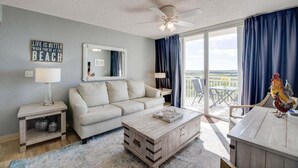 Un salon avec un canapé, une table basse et un balcon offrant une vue agréable.