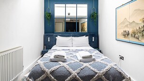 A bedroom with a large bed, a window with a view, and a painting on the wall.