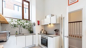 A compact kitchen with white cabinets, a stainless steel stove, and a tiled backsplash.