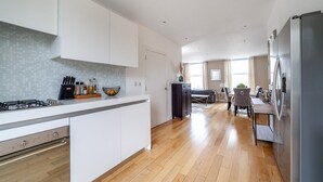 A modern kitchen with white cabinets, a wooden countertop, and a stainless steel refrigerator.