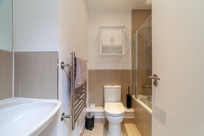 A compact bathroom with a bathtub, toilet, and shower.