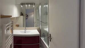 Un baño moderno con lavamanos blanco, un espejo y cabina de ducha de vidrio.