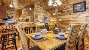 Ein Holzblockbau von innen mit Essbereich, Holzwänden und Deckenleuchten.