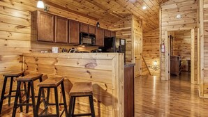 Innenansicht einer Holzhütte mit Küchenzeile, Barhocker und Feuerlöscher.