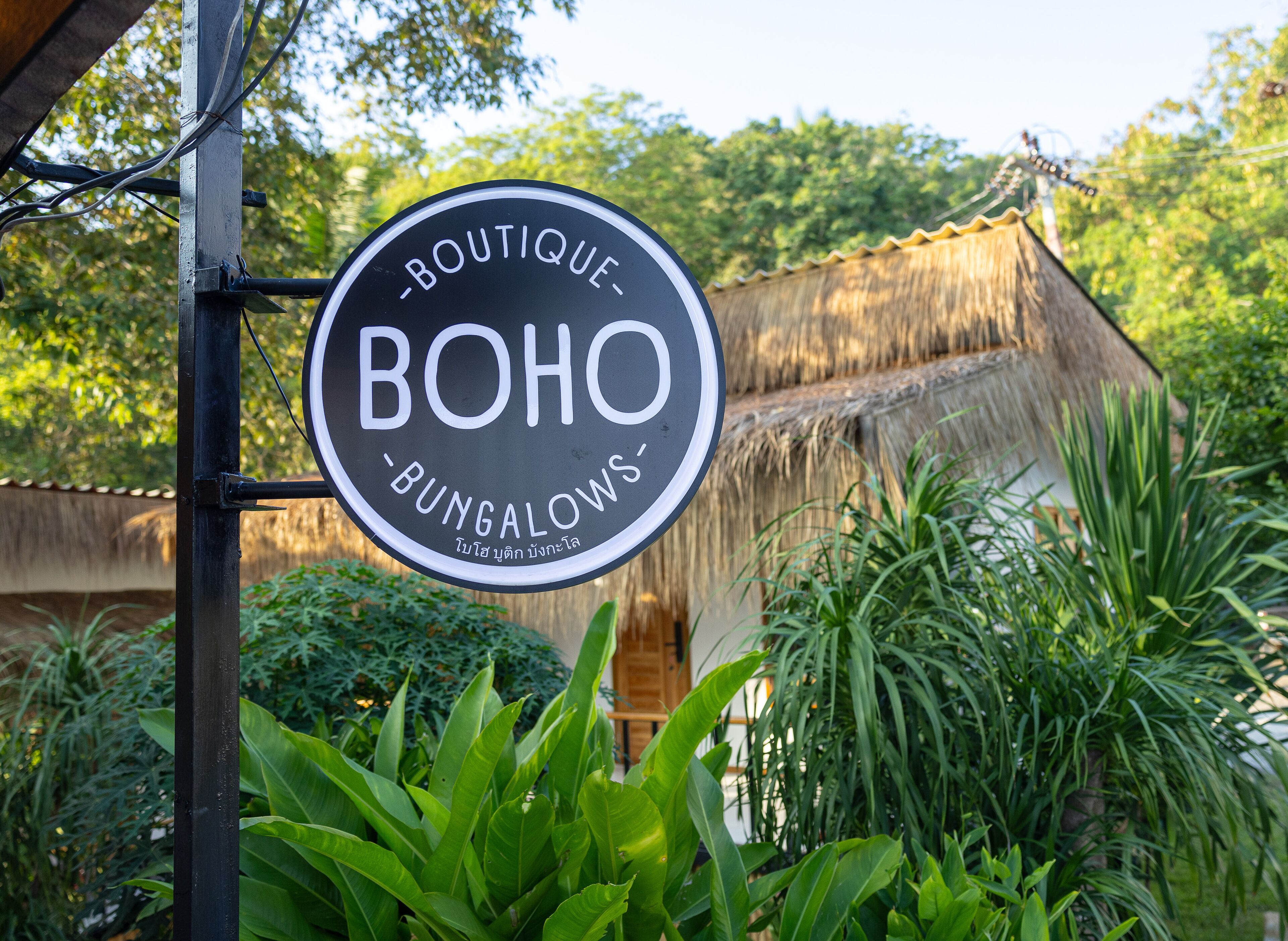 A sign for 'BOHO BUNGALOWS' with a thatched-roof building in the background.