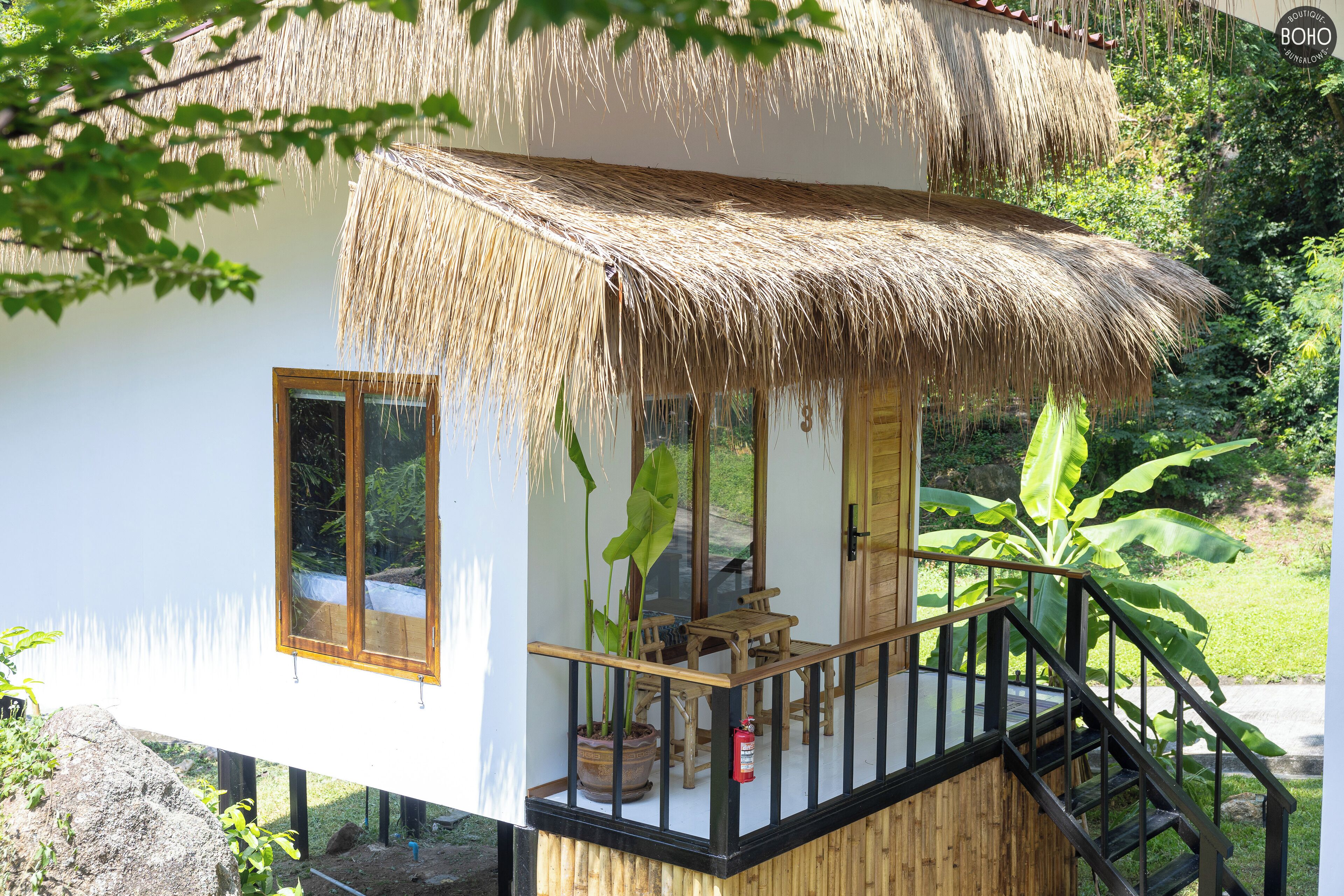 Ein Reetdachbungalow mit Holzbalkon, einem Blumentopf und einem Feuerlöscher.