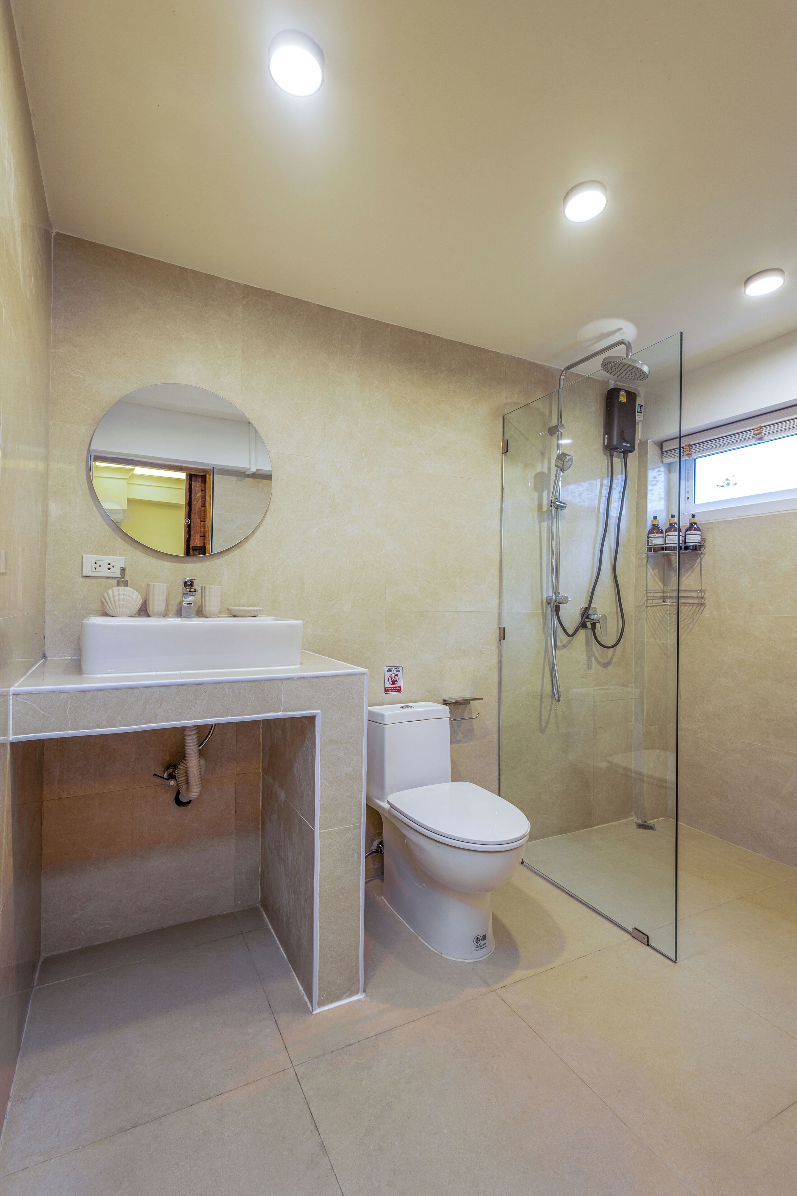 A modern bathroom with a glass-enclosed shower, a white sink, and a toilet.