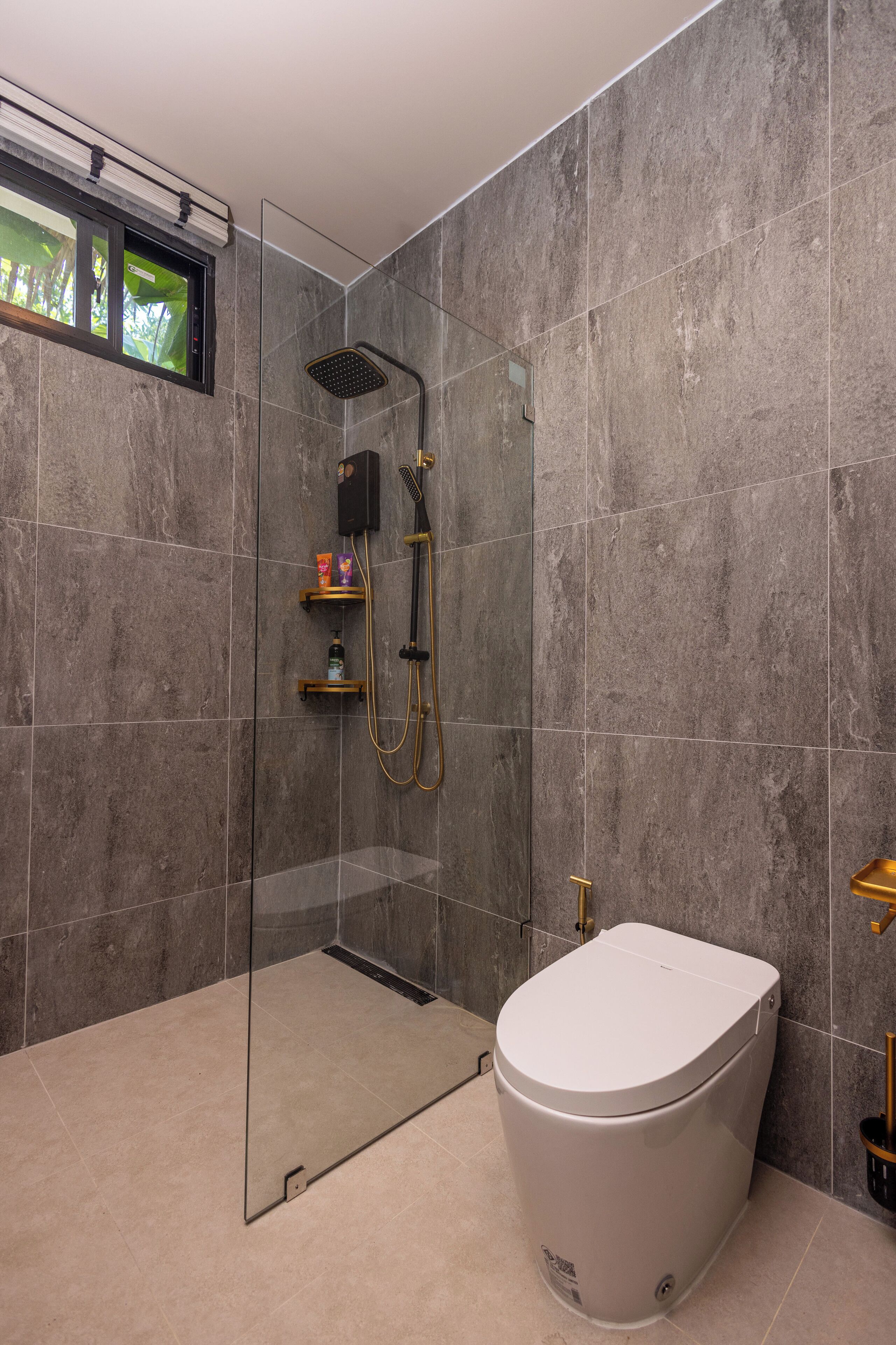 A modern bathroom with a glass-enclosed shower, a toilet, and a small shelf with toiletries.
