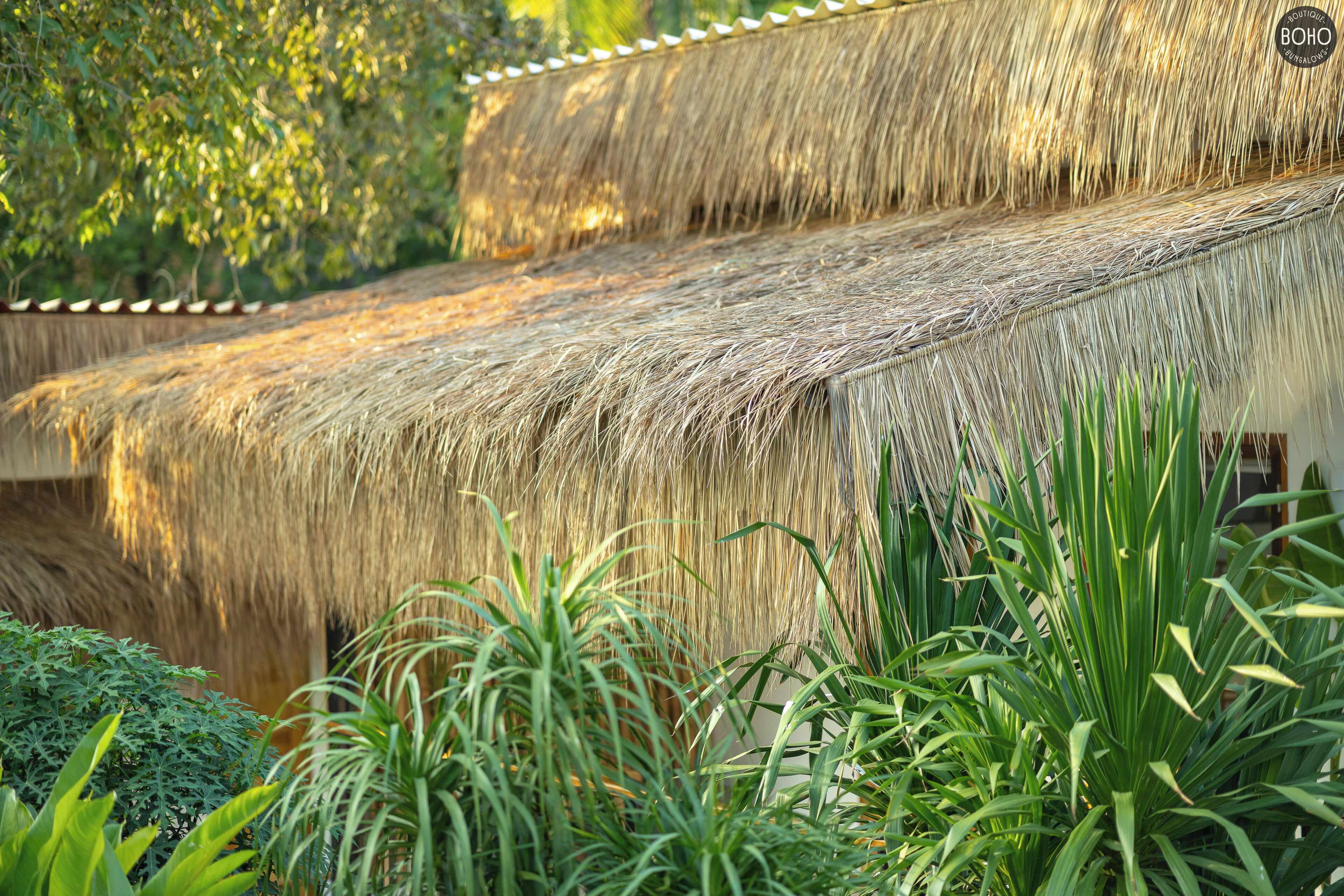 Estructura de techo de paja con diseño escalonado, rodeada de exuberante vegetación.