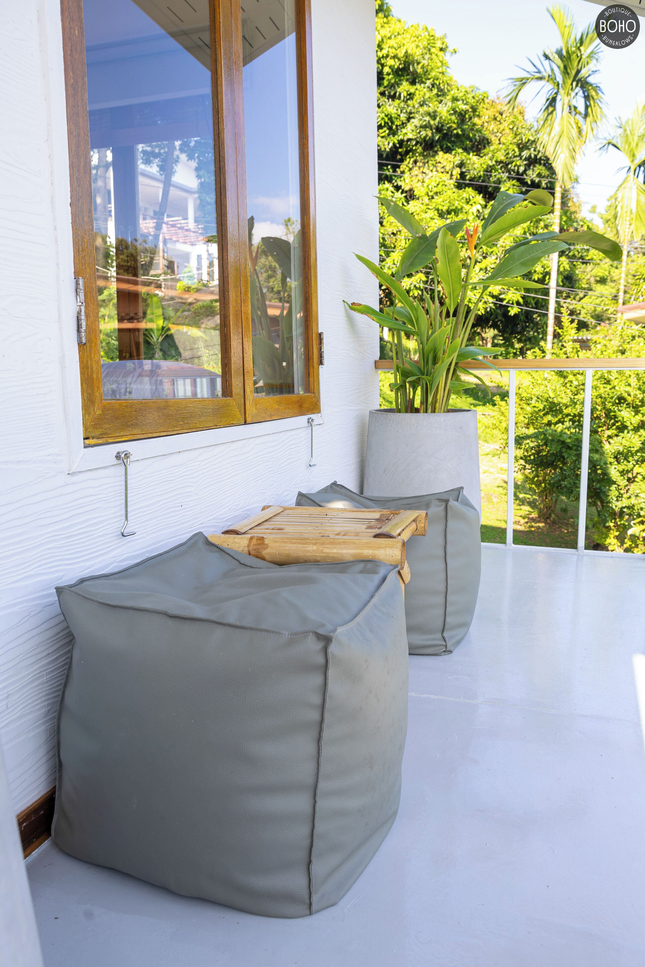 A balcony with a white railing, a large window, and a potted plant.