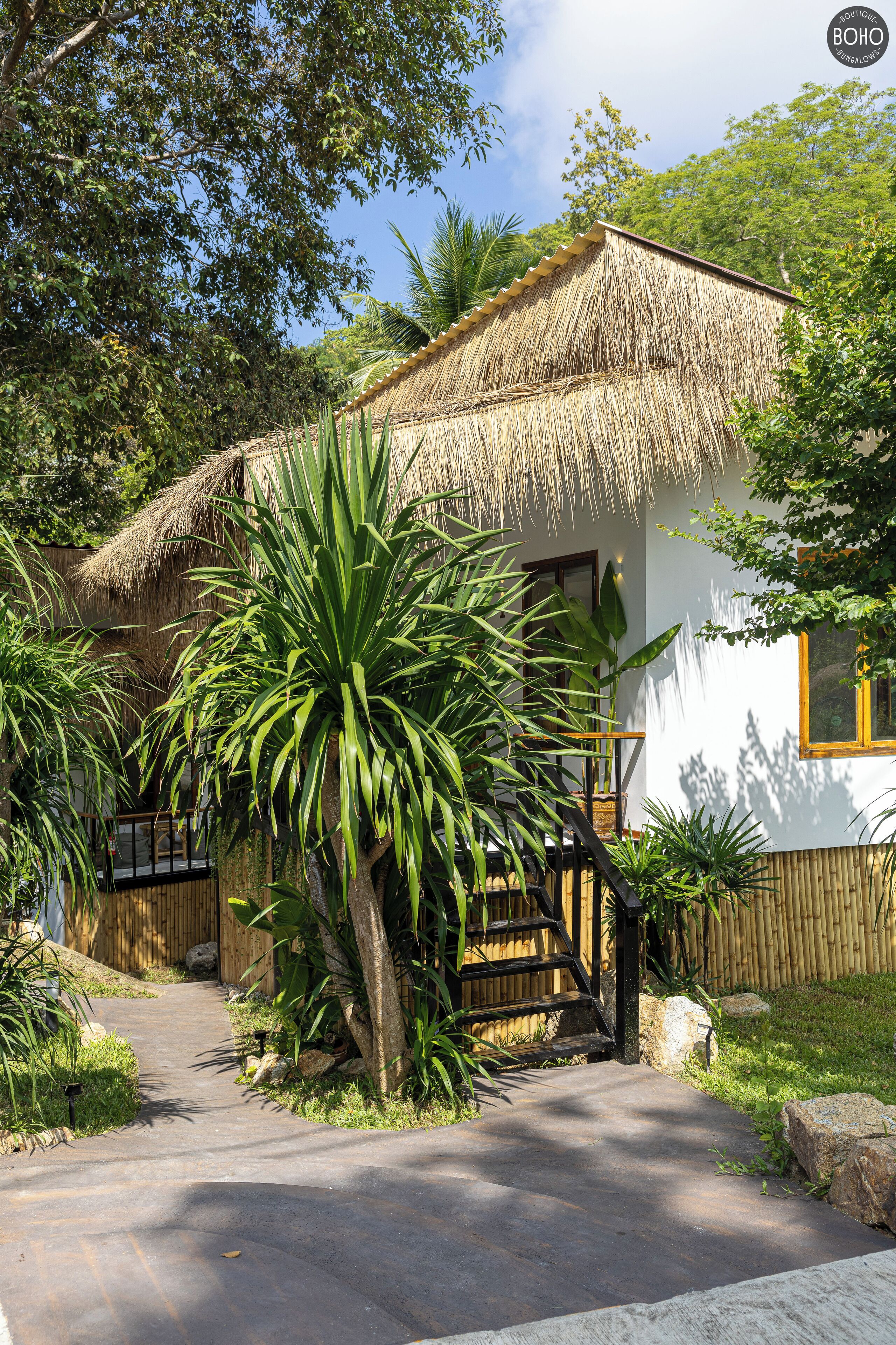 A thatched-roof house with a wooden staircase leading to a white door.