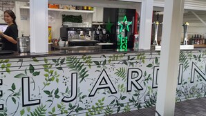Zona de bar con un letrero de neón con una estrella, una máquina de café y una barra con un cartel que dice 