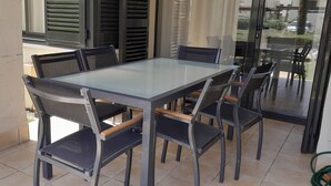 Una mesa de comedor con cubierta de vidrio y seis sillas, una puerta corrediza de cristal y vistas al exterior.