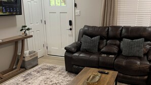 A living room with a brown leather sofa, a wooden coffee table, and a patterned rug.