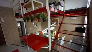 Un interno moderno con un tavolo rosso, ringhiere in vetro e piante in vaso.