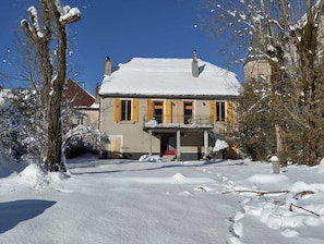 A two-story house with a snow-covered roof and a balcony. - Jura-style house with a garden in the heart of the village of Mouthe (Mouthe)
