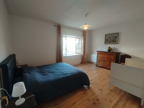 A bedroom with a bed, a nightstand, a dresser, a window with curtains, and a ceiling fan. - Jura-style house with a garden in the heart of the village of Mouthe (Mouthe)