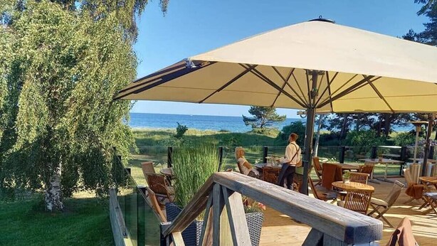 Terraza de madera con mobiliario exterior y un gran paraguas.