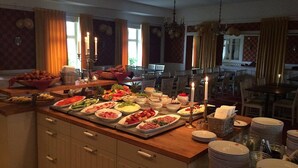 Montaje de bufé con diversos platos y un comedor con sillas y mesas.
