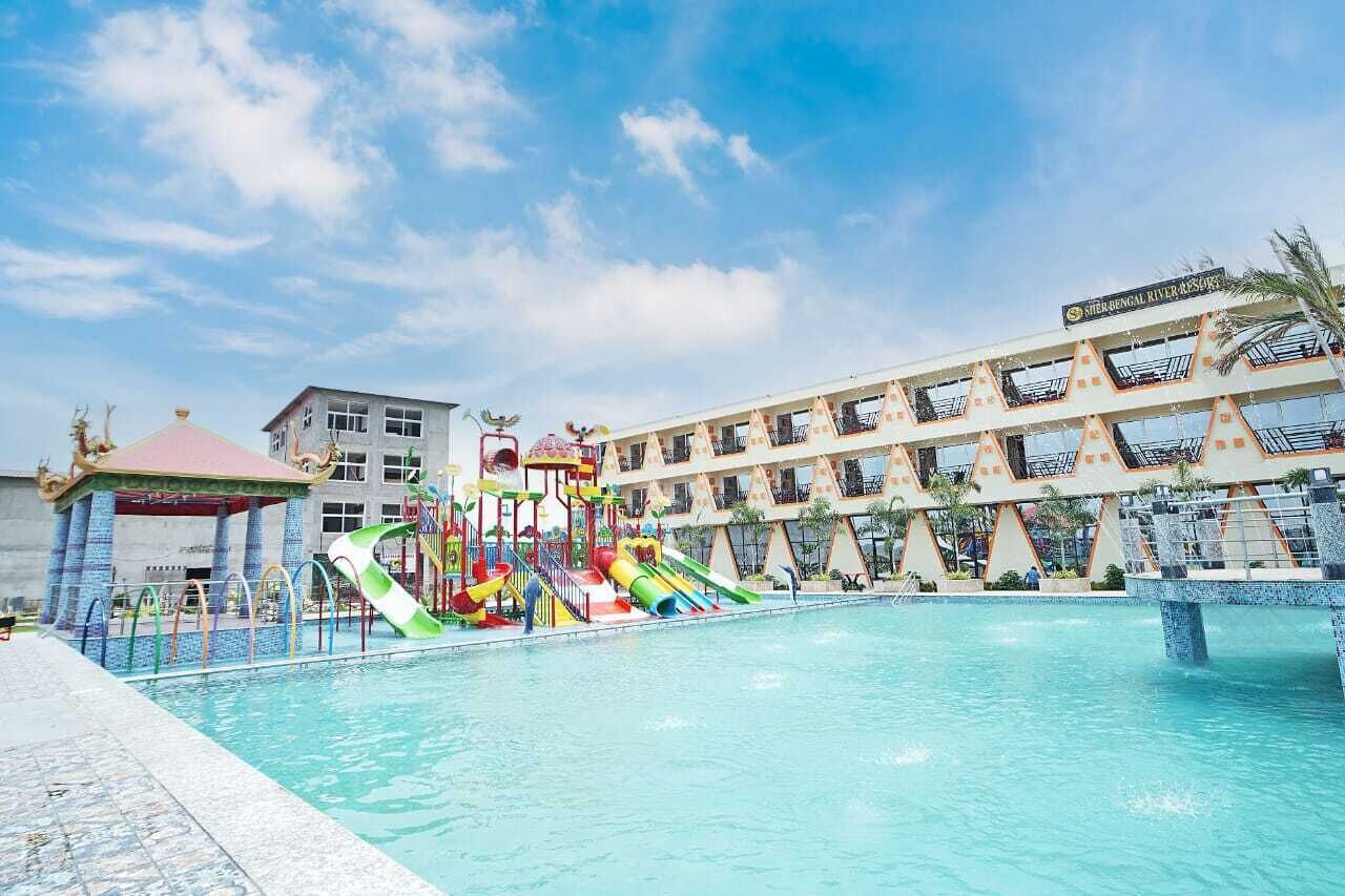 Ein Schwimmbecken mit Wasserrutsche und ein Gebäude mit Balkonen im Hintergrund.
