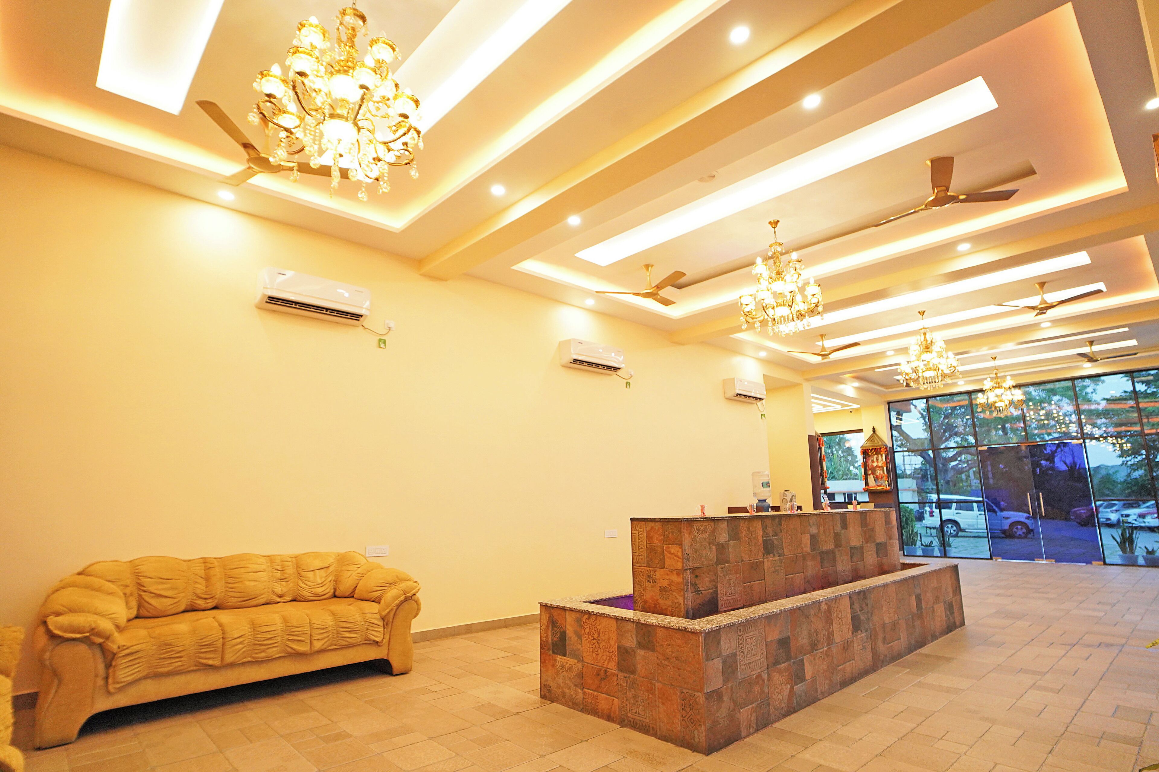 A reception area with a sofa, a reception desk, ceiling fans, and chandeliers.