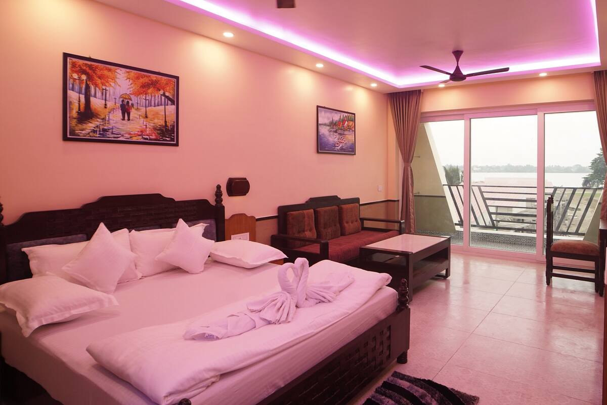 A hotel room with a bed, a desk, a chair, and a balcony with a view.